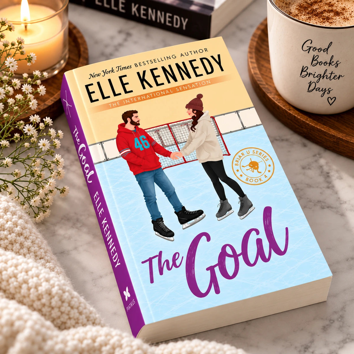 The Goal by Elle Kennedy book displayed on a marble table with coffee, candle, flowers, and cozy decor